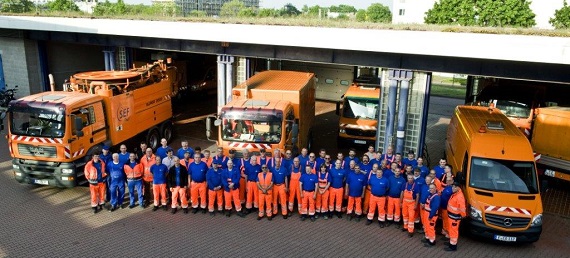 Gruppenbild Team städtischen Kanalisation vor orangenen LKW.